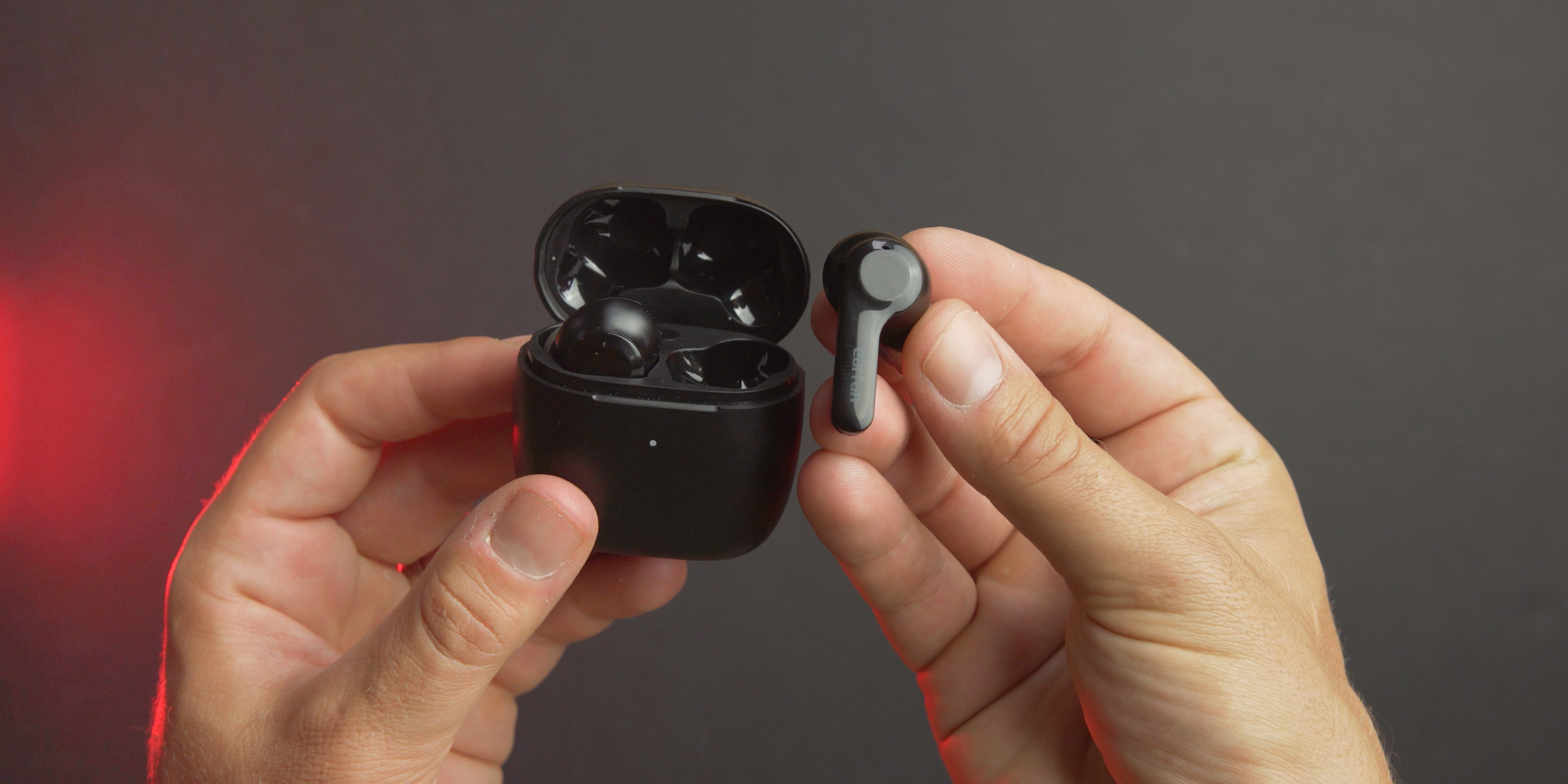 Holding the EarFun Air earbud next to its charging case