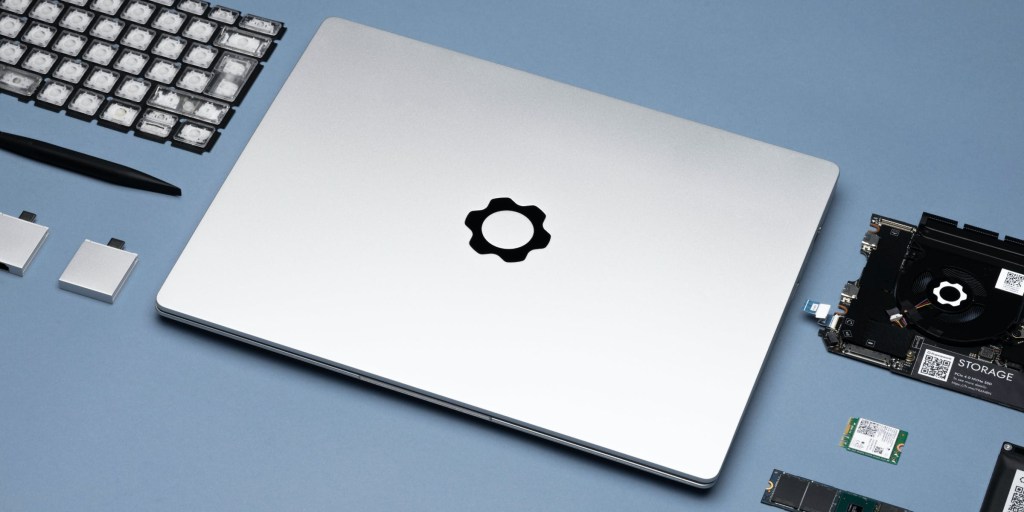 Framework's modular laptop with exchangeable parts splayed out on a gray blue surface.