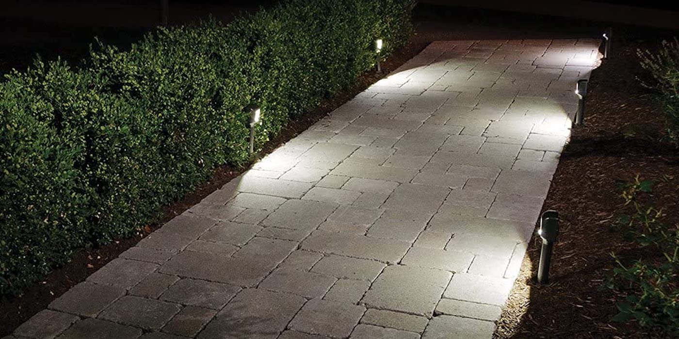 an empty sidewalk in front of a brick wall