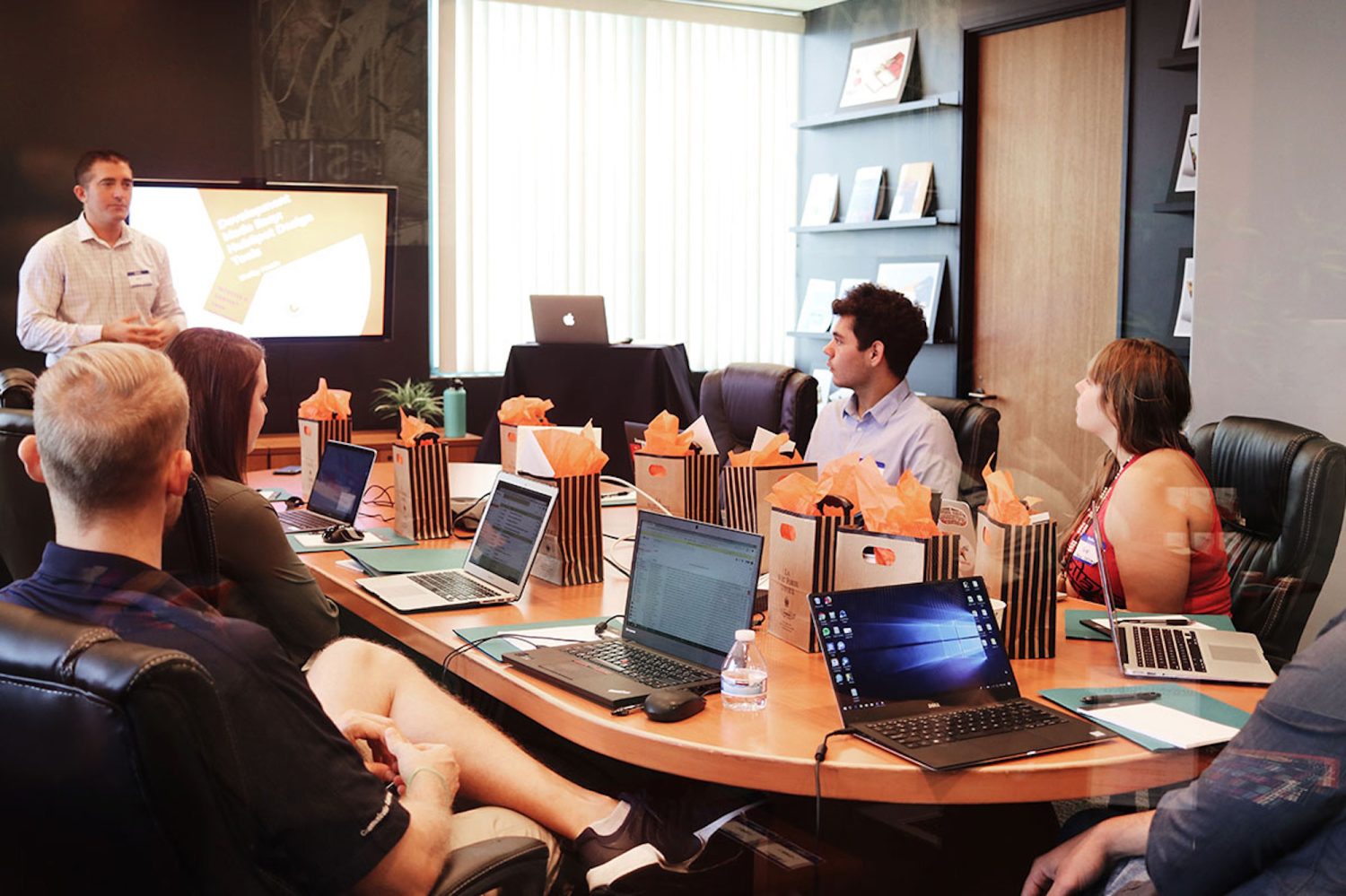 a group of people sitting at a table using a laptop computer