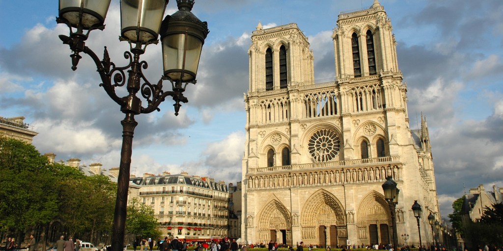 a group of people standing in front of a large church with Notre Dame de Paris in the background