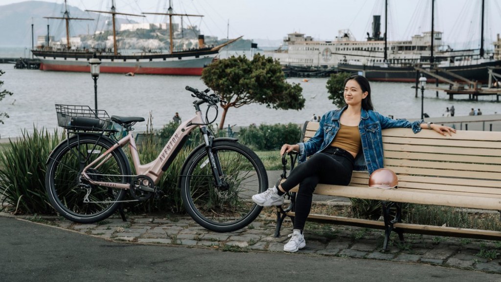a woman sitting on a bench next to a bicycle