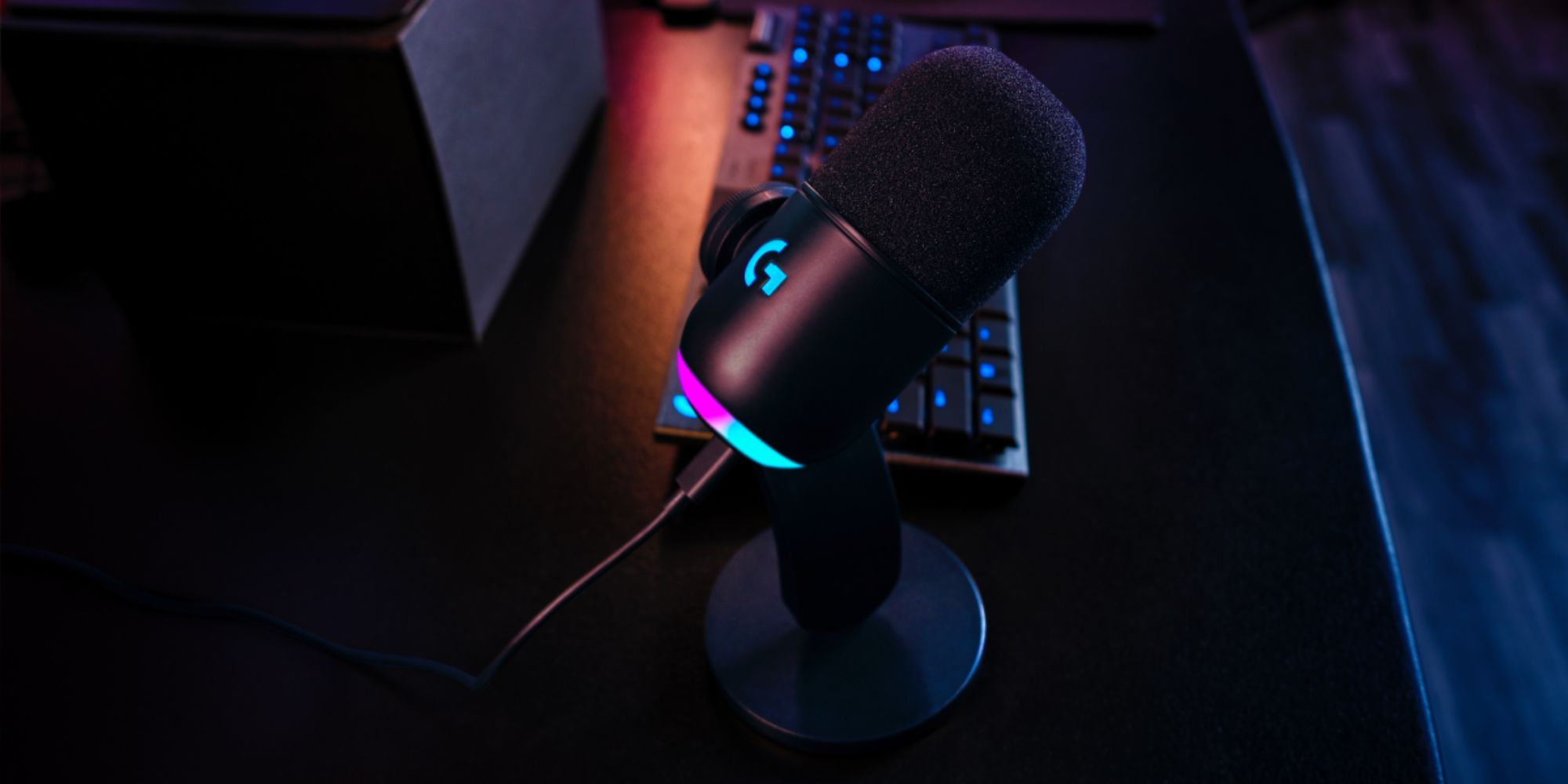 Logitech G Yeti GX mic with RGB lighting kept on a table next to other peripherals.
