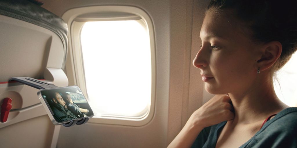 Person watching a video on a phone mounted to an airplane seat.