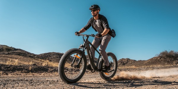 a man riding a bike on a dirt road