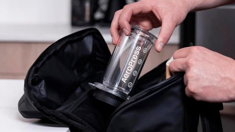 A person putting a plastic cup into a bag