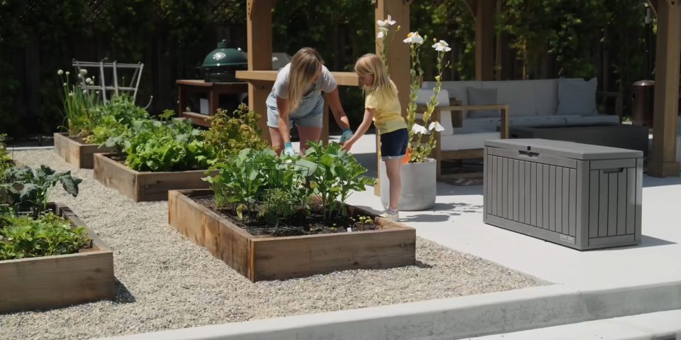 A woman and a girl planting plants in a garden