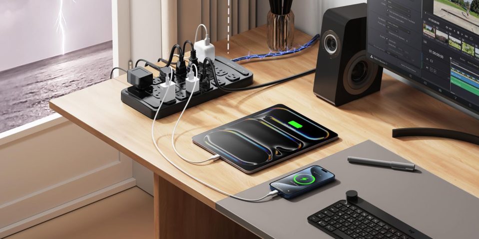 A table with a power strip and a phone and a speaker