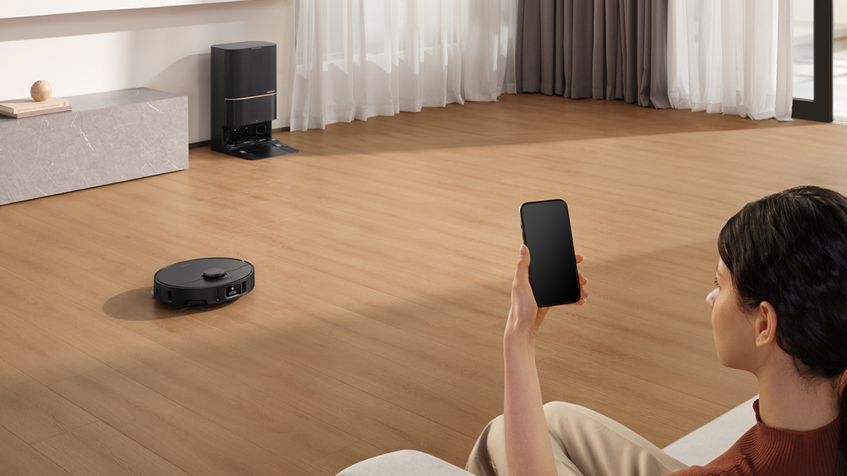 A person holding a phone in front of a vacuum cleaner