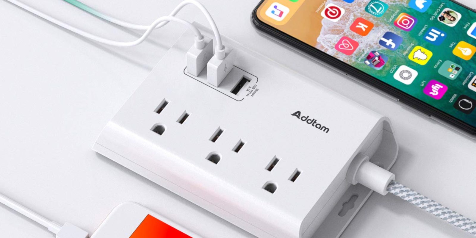 A white power strip with a phone and a cell phone