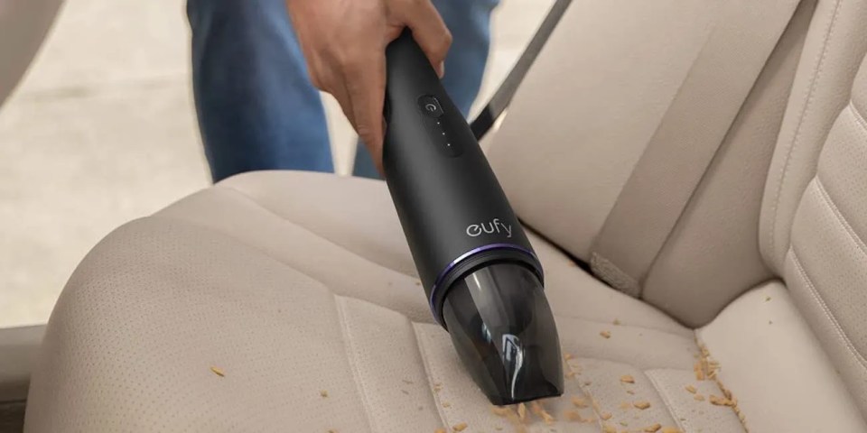 A person vacuuming a car seat