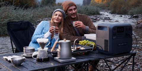 A man and woman sitting at a table with food and drinks