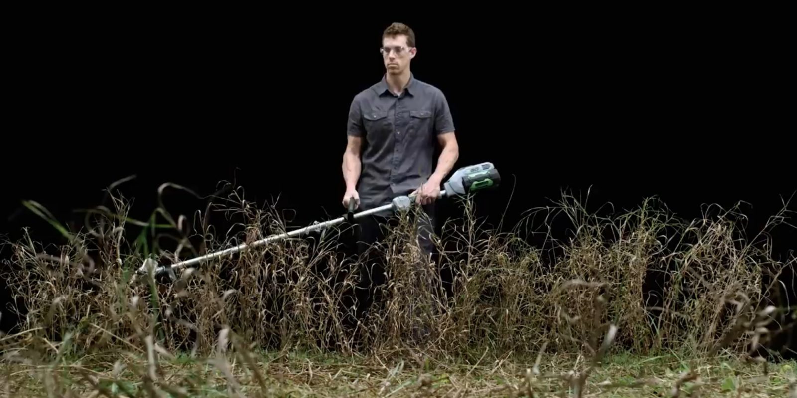 A man holding a trimmer in a field