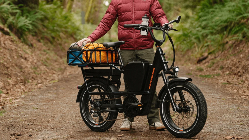 A person standing next to a black electric bike