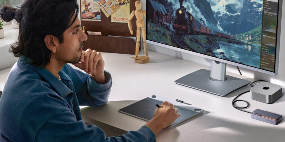 A man sitting at a desk with a computer and a tablet