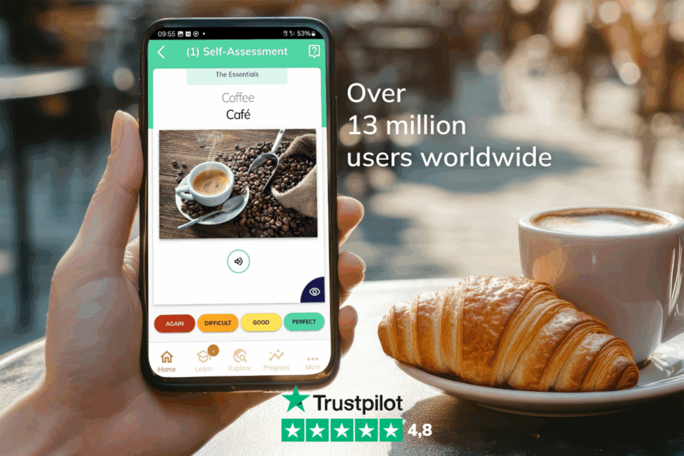 A hand holding a phone with a cup of coffee and a croissant