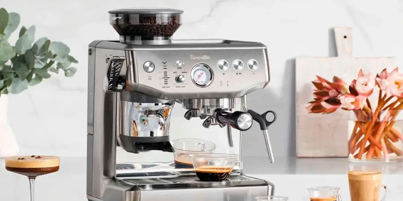A silver espresso machine with a glass bowl of coffee