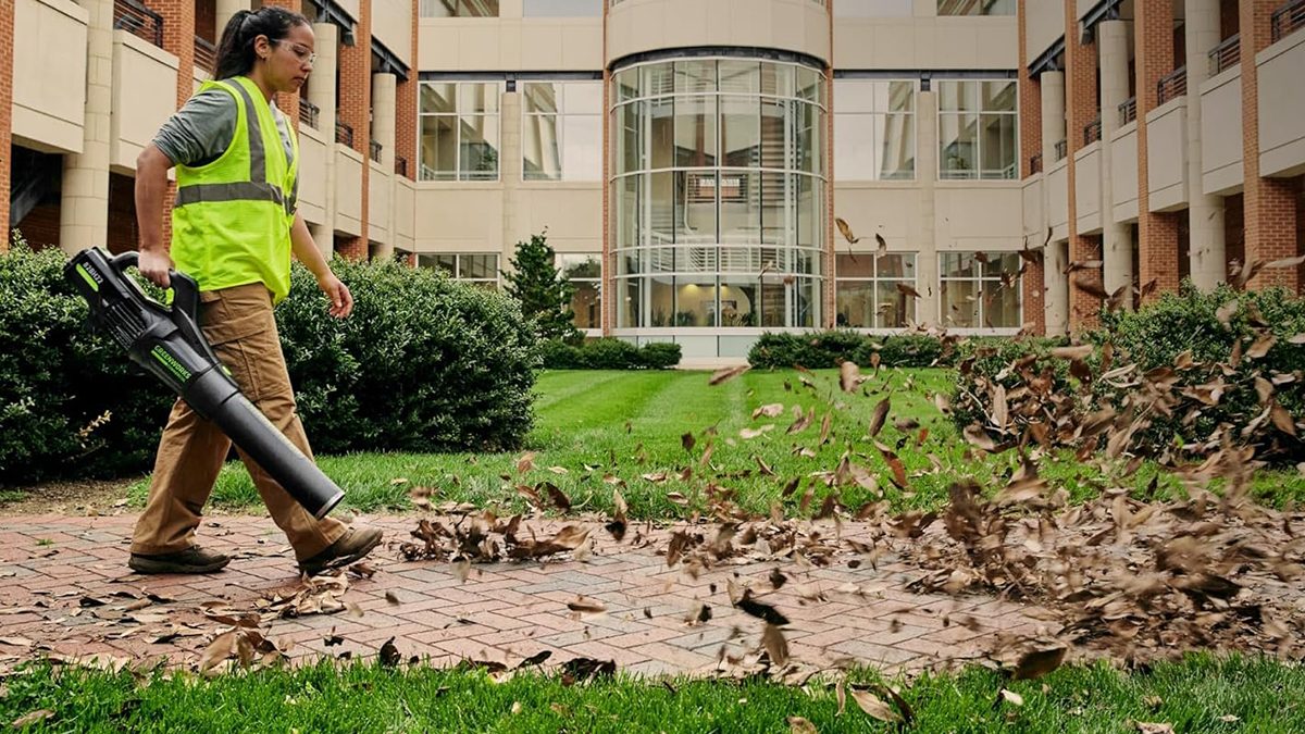 A woman in a vest sweeping leaves