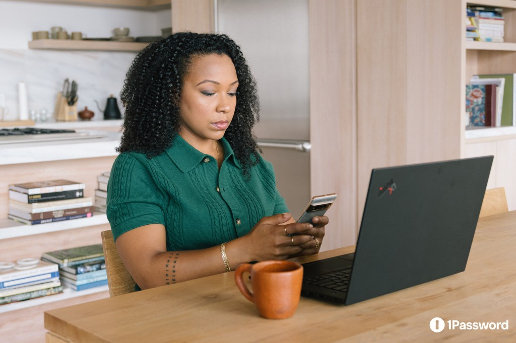 A woman sitting at a table with a laptop and a phone