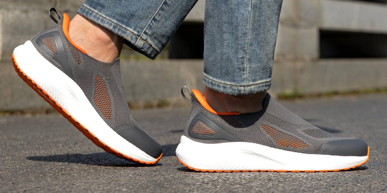 A person's feet wearing gray and orange shoes