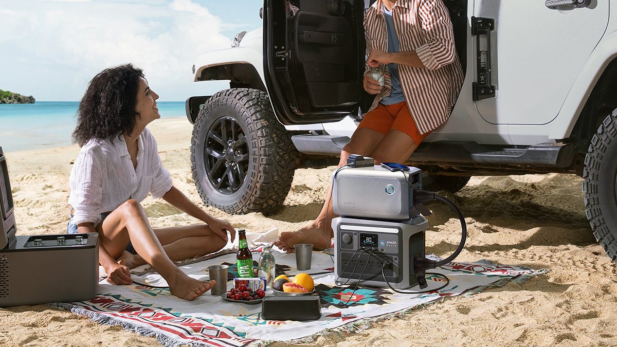 A couple of people sitting on a blanket next to a car