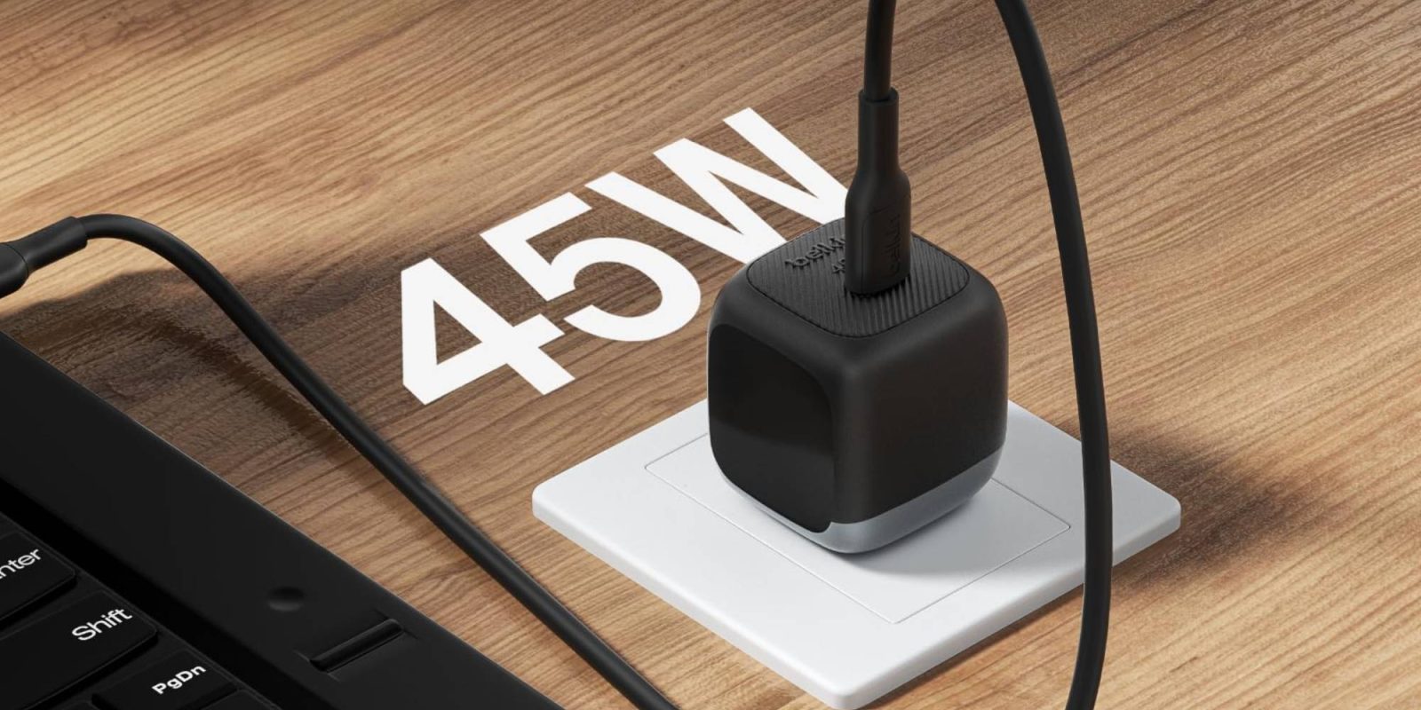 A black cube with a cord plugged into a white outlet