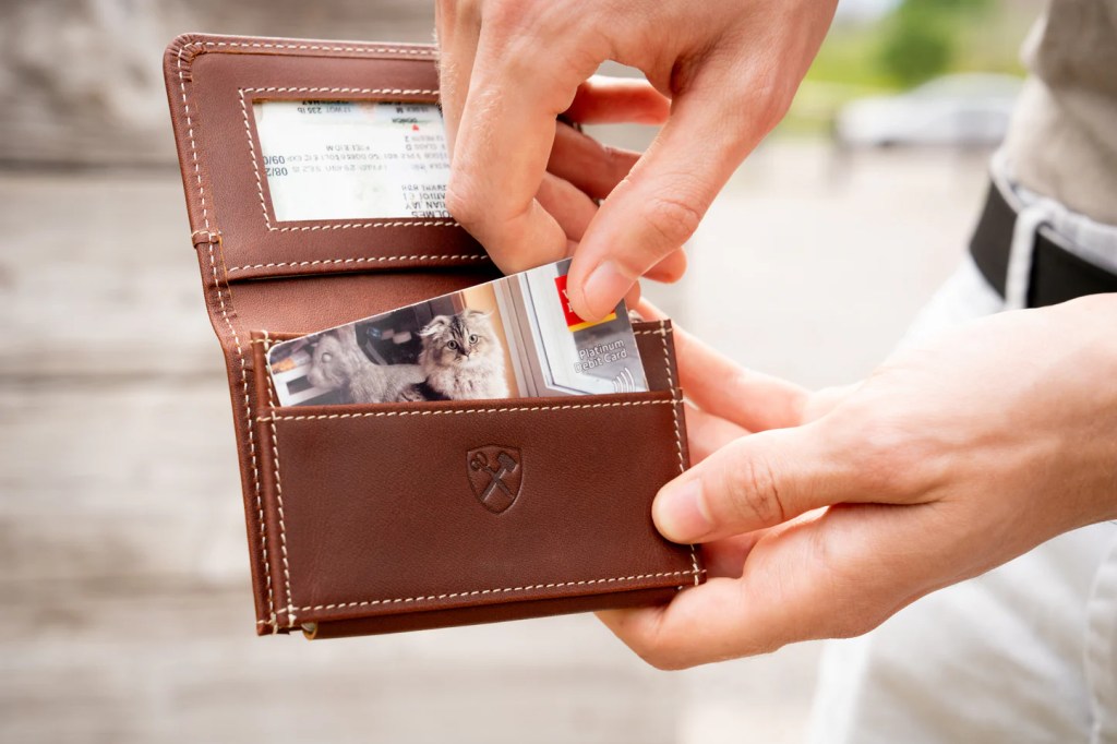 A person holding a wallet with a card in it