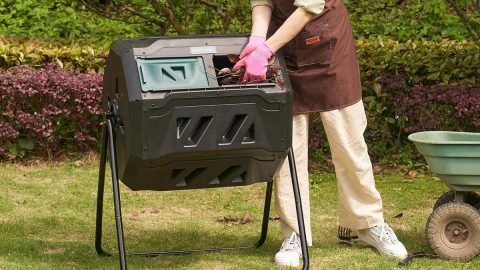 A person putting leaves into a compost bin