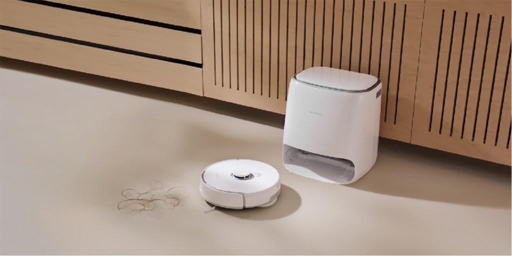 A robot vacuum cleaner next to a wood cabinet