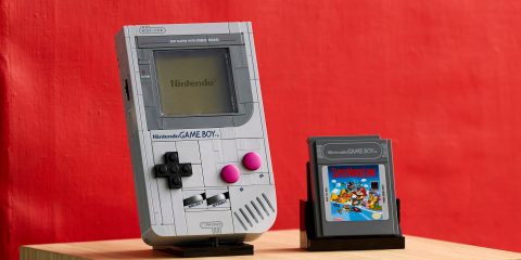 A grey handheld video game console next to a grey handheld video game cartridge