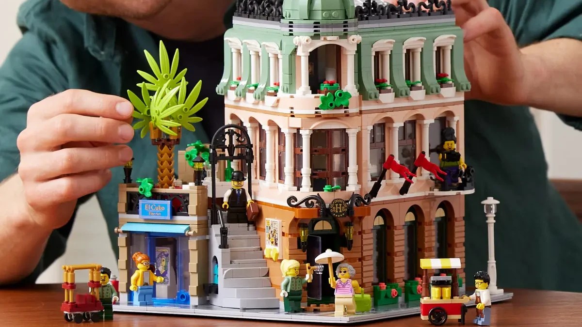 A person holding a building made of legos