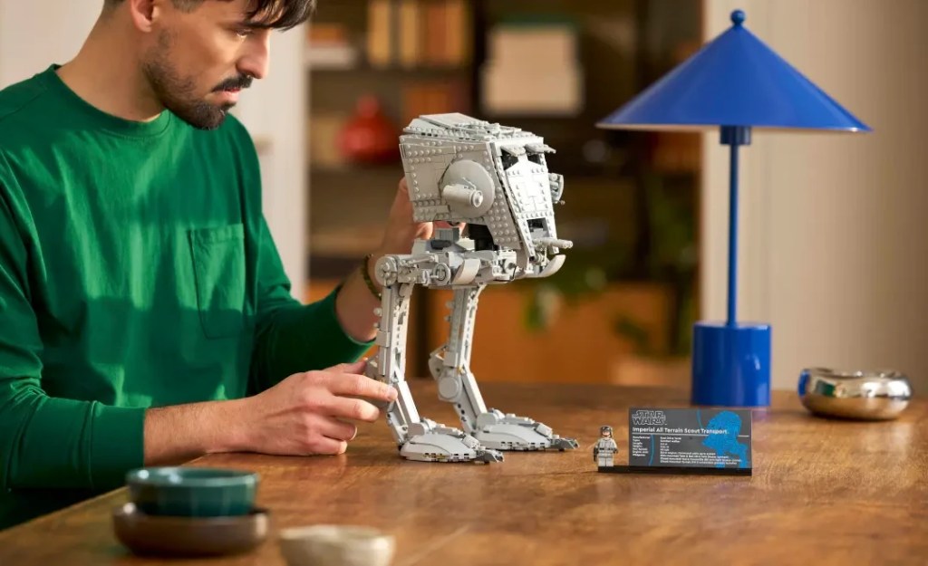 A man looking at a LEGO Star Wars AT-ST Walker set