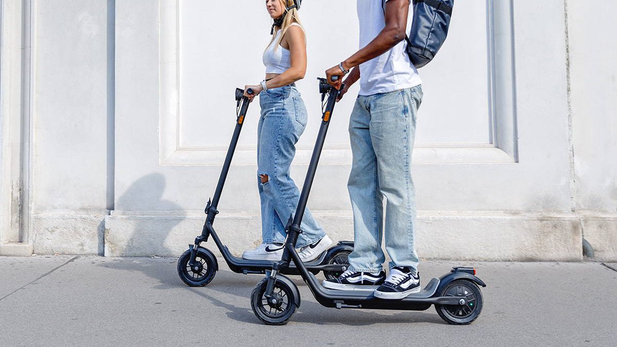 A man and woman riding scooters