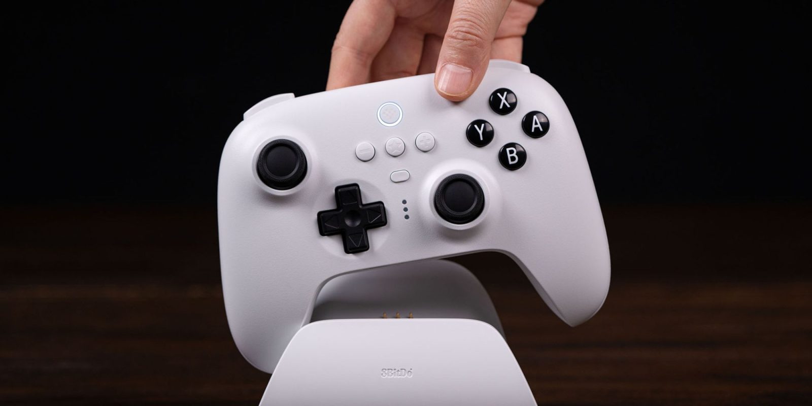 Image showing a person docking 8Bitdo's Ultimate controller in white.
