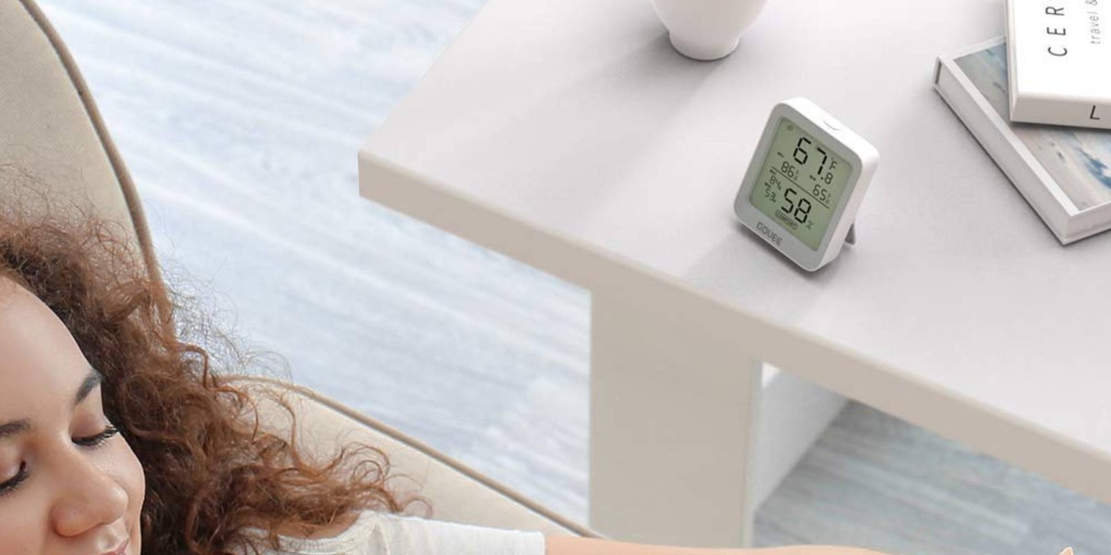 A woman sitting on a couch with a digital clock
