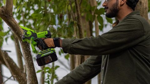 A man holding a green and black cordless drill