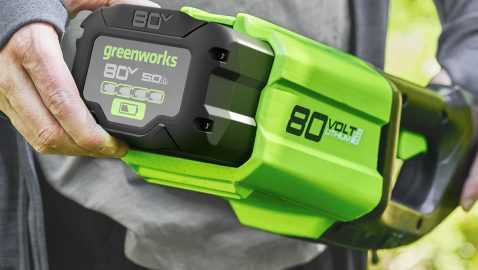 A person holding a green and black battery