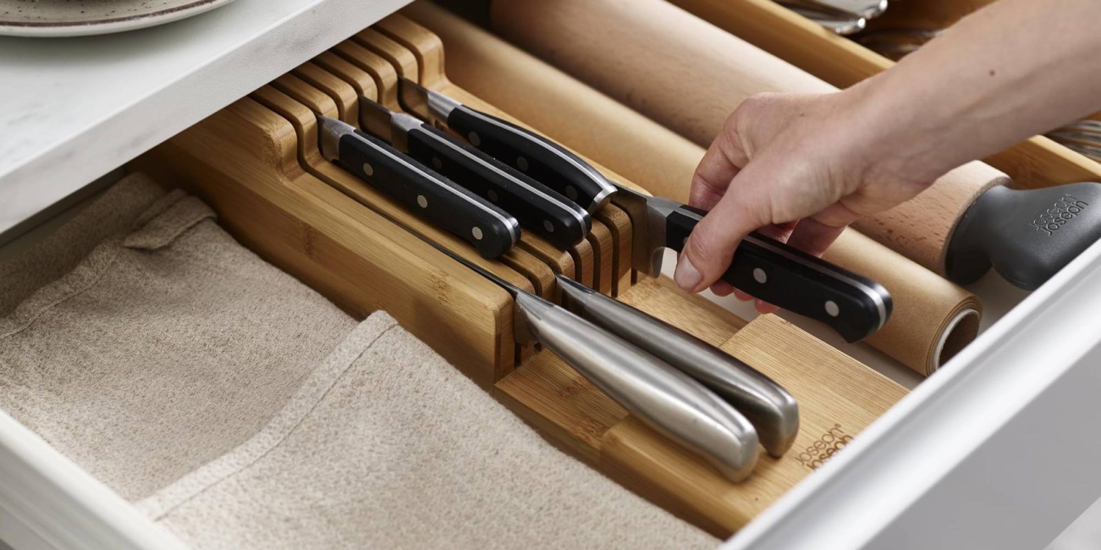 A hand holding a knife in a drawer