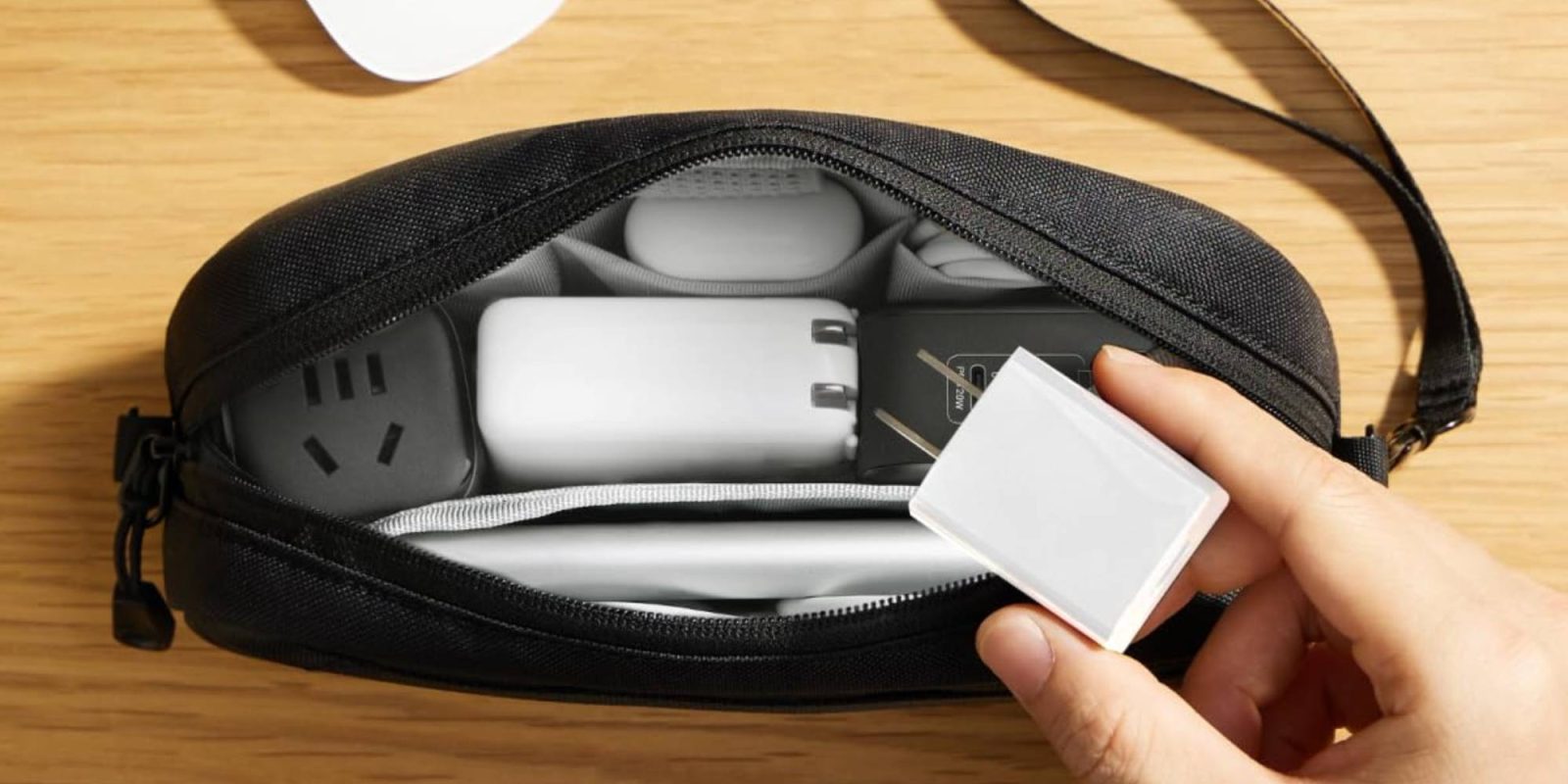 A hand holding a white device in a black bag