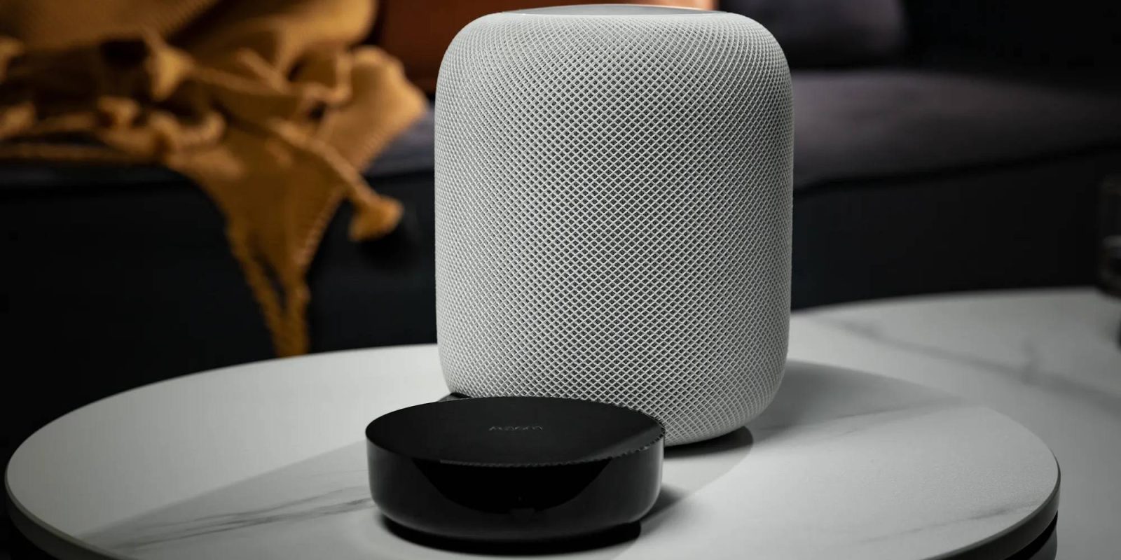 A white speaker next to a black round object