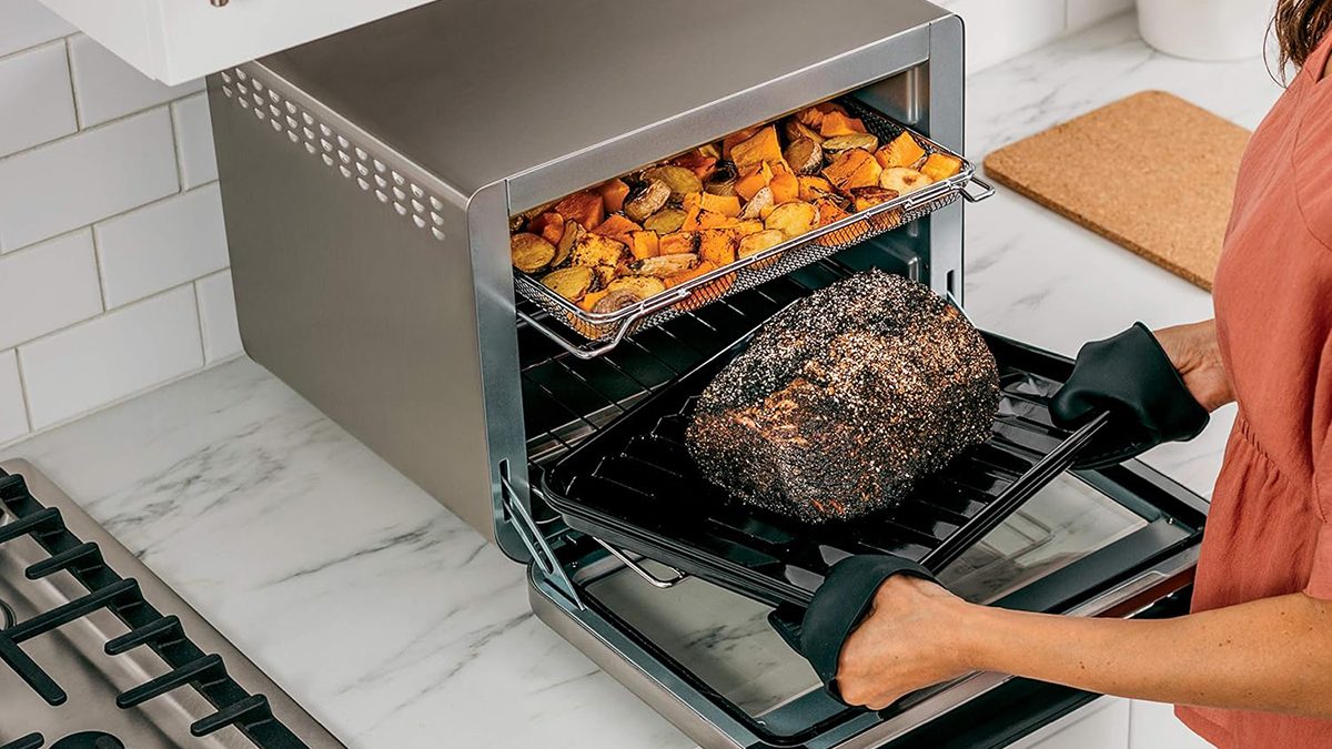 A hand holding a tray of food in an oven