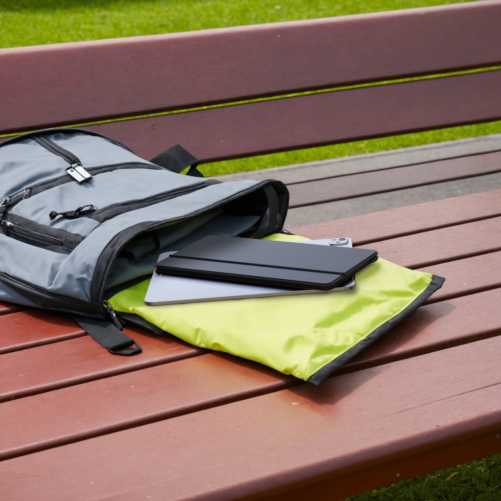 A backpack with a tablet and a case on a bench