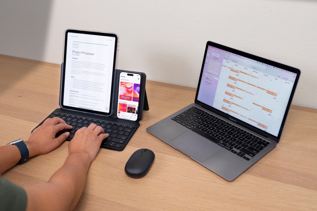 A person using a laptop and a phone