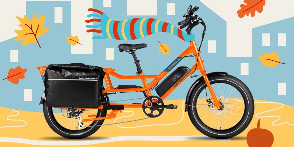An orange bicycle with a bag on it