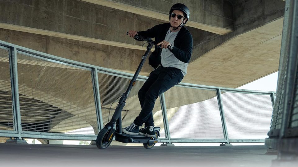 A man riding a scooter under a bridge