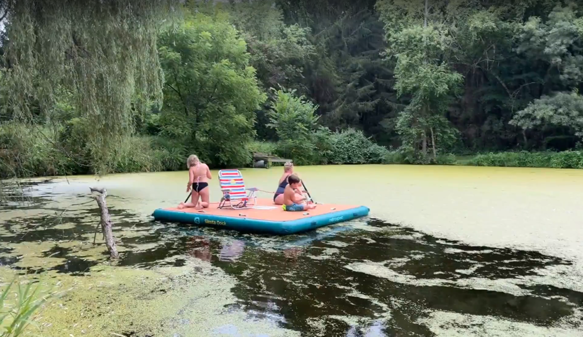 A group of kids on a floating platform in a lake