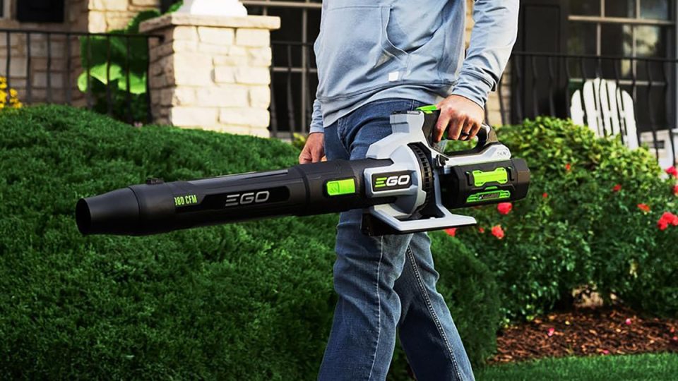 A man holding a large black and green leaf blower