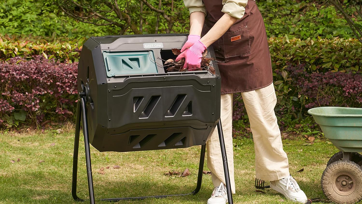A person putting leaves into a compost bin
