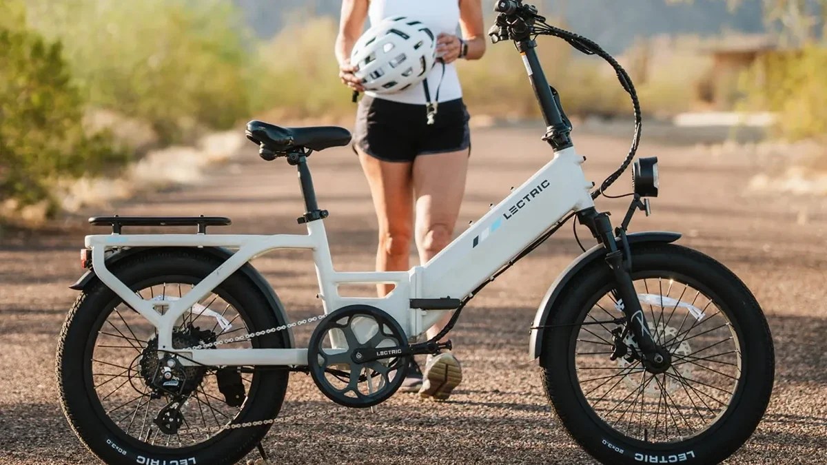 A woman standing on a dirt road with a white bicycle