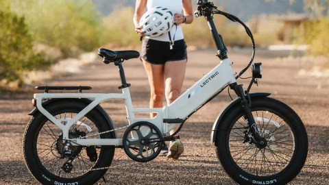 A woman standing on a dirt road with a white bicycle